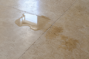 Water being absorbed into a natural travertine floor, demonstrating the porous nature of travertine stone and how moisture can penetrate unsealed surfaces.
